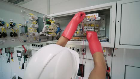 el ingeniero eléctrico que trabaja comprueba la tensión de corriente eléctrica y la sobrecarga en la parte delantera del gabinete del centro de carga o de la unidad de consumo para el mantenimiento en la sala principal del sistema de distribución de energía.