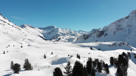 drone view of snow-covered mountain ranges in vorarlberg, austria on a clear sunny day with blue skies in 4k