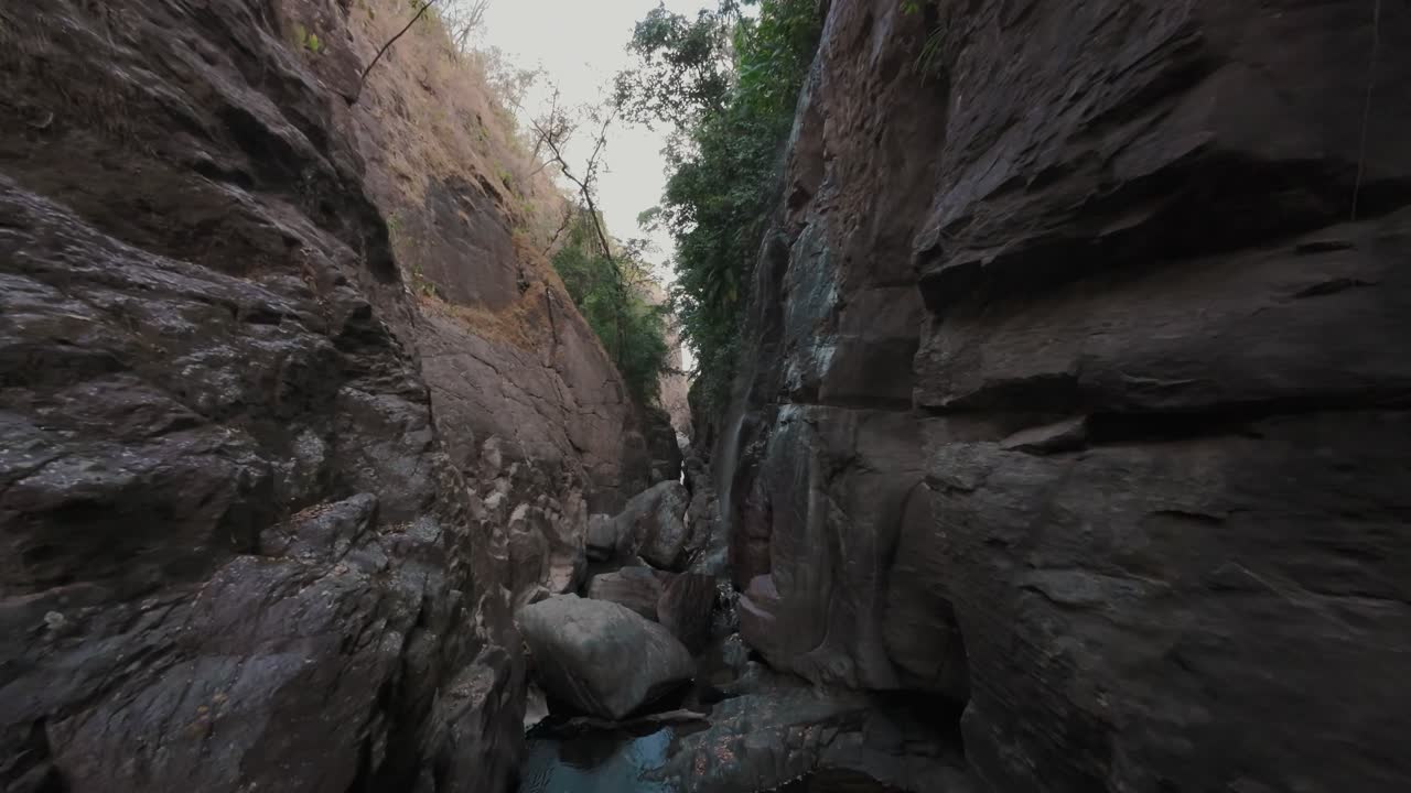 Vol en FPV à basse altitude dans un canyon étroit du lit de la rivière Raizama, navigation entre de gros rochers et exploration du paysage rocheux du parc national de Chapada dos Veadeiros, Brésil