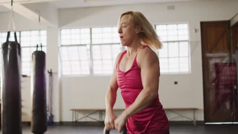 fit caucasian woman working out with kettle bell at the gym