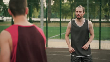 Dos-Jugadores-De-Baloncesto-Masculino-Pasándose-La-Pelota-Durante-Una-Sesión-De-Entrenamiento-En-Una-Cancha-De-Baloncesto-Al-Aire-Libre