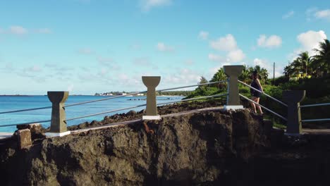 drone shot of a girl walking towards the cliff of taga beach, tinian island