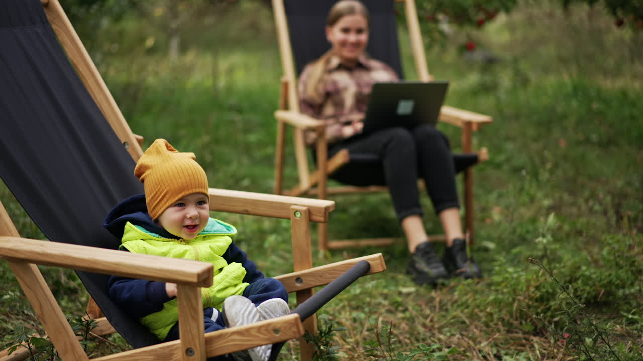 Mother working remotely with her baby in an apple orchard