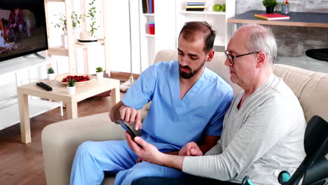 joven médico enseñando a un anciano a usar su teléfono inteligente