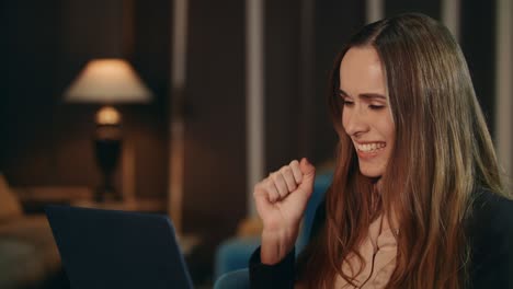 excited business woman reading good news on laptop computer in hotel at evening