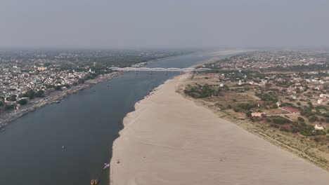 aerial shot of the densely packed neighborhoods of varanasi, with the ganges cutting through the city's heart, reflecting the spiritual pulse of india.