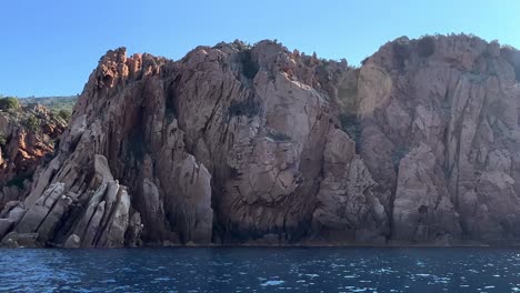 primordial calanques de piana volcanic eroded rock formations in corsica island as seen from moving boat in summer season, france