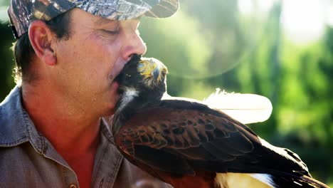 man kissing falcon on a sunny day