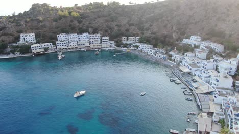 vista de avión no tripulado en grecia panorámica sobre el mar azul claro en loutro pequeña ciudad de casas blancas y pequeños barcos al lado de una colina en un día soleado