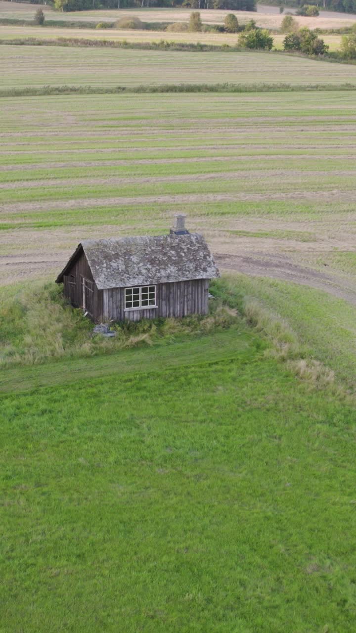 Gammelt træsmedeværksted omgivet af grønne marker i det landlige Sverige