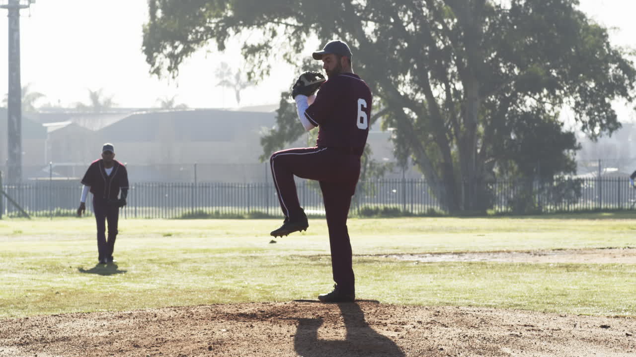 Giocatori di baseball maschi multietnici che giocano a baseball, lanciando la palla su un campo, al rallentatore.