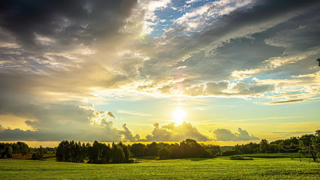 toma de lapso de tiempo del sol que se levanta sobre las praderas verdes con nubes oscuras que pasan al amanecer