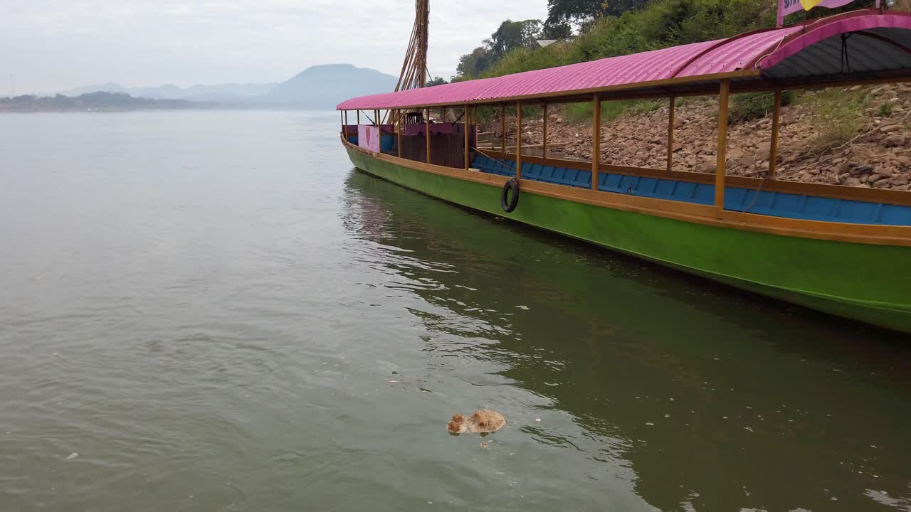 un bote vacío de cola larga de madera que atraca en un mar en calma cerca de una costa rocosa en tailandia - plano medio, estático