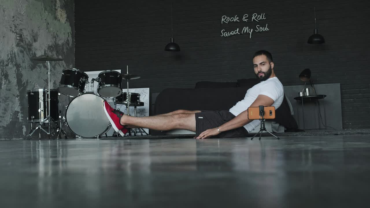 joven haciendo ejercicios en el estudio de música y lo dispara en el teléfono.