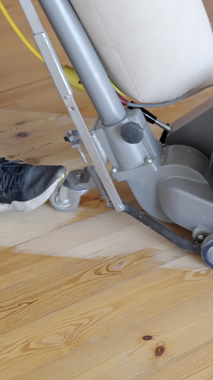 Floor sanding in progress with worker moving drum sander, vertical