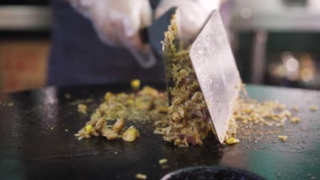 chef stir frying meat with rice on griddle pan