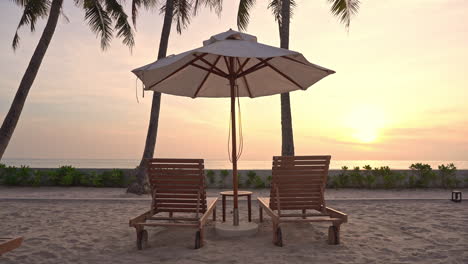 resort beach chairs and sun umbrella close to seashore at sunset