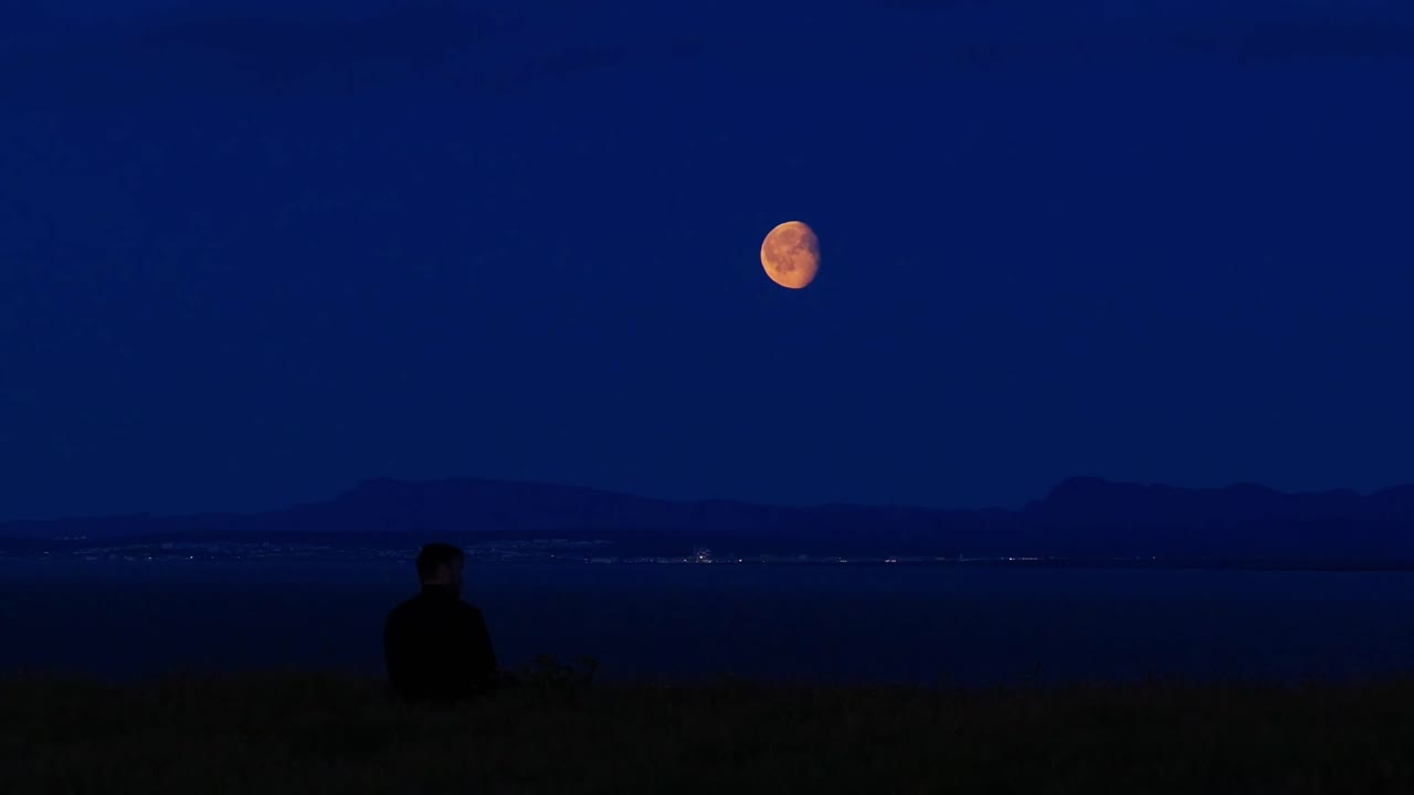 레이캬네스 절벽에서 북대서양 위 거대한 달을 바라보는 젊은 남자의 뒷모습. 케플라비크