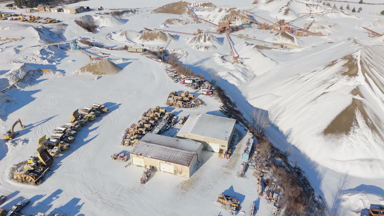 Gravel quarry covered in snow with heavy machinery and conveyors in winter landscape