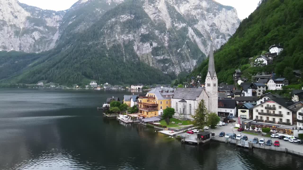 Hallstattin kylä Itävallassa Hallstatt-järven rannalla Salzkammergutin alppialueella. Ilmakuva järvenrantakirkosta, historiallisista taloista, tyynestä vedestä ja jyrkistä alppivuorista.