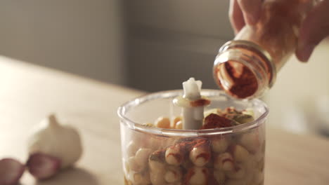 adding spices to hummus ingredients in a food processor