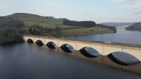 vuelo aéreo de drones sobre el embalse de ladybower en derwent vally en el distrito de los picos que se desplaza lentamente alrededor del puente dando una vista de los bosques