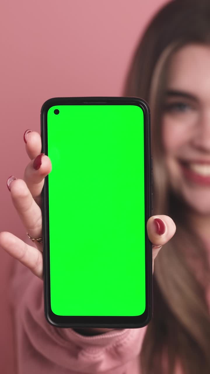 Cheerful young woman showing smartphone with chromakey