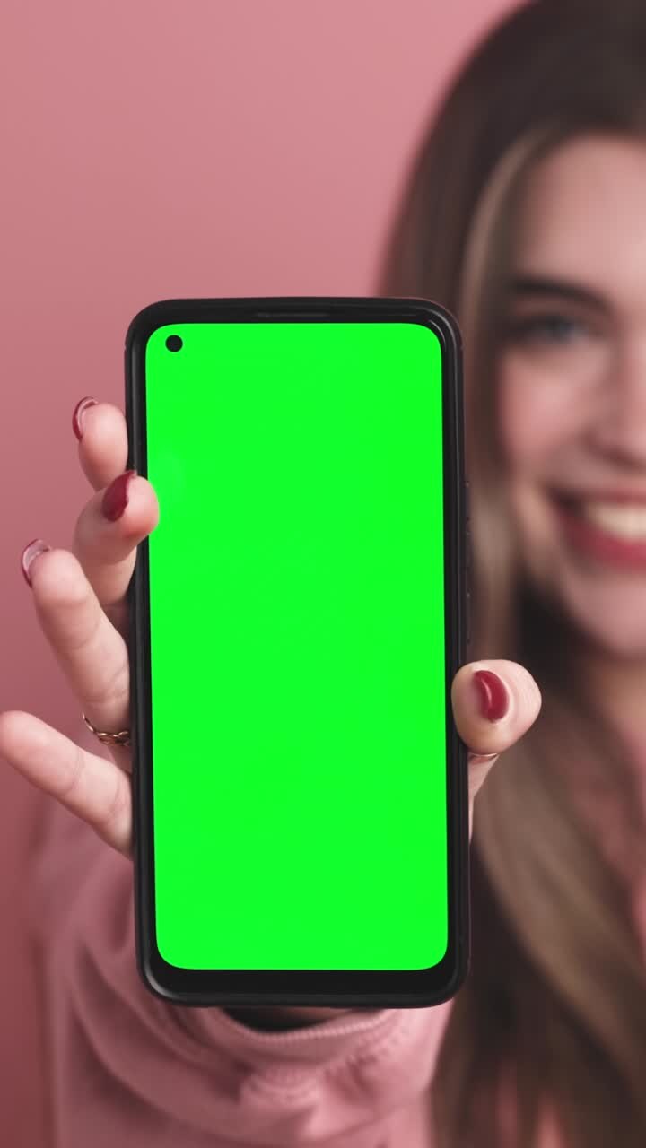 Cheerful young woman showing smartphone with chromakey