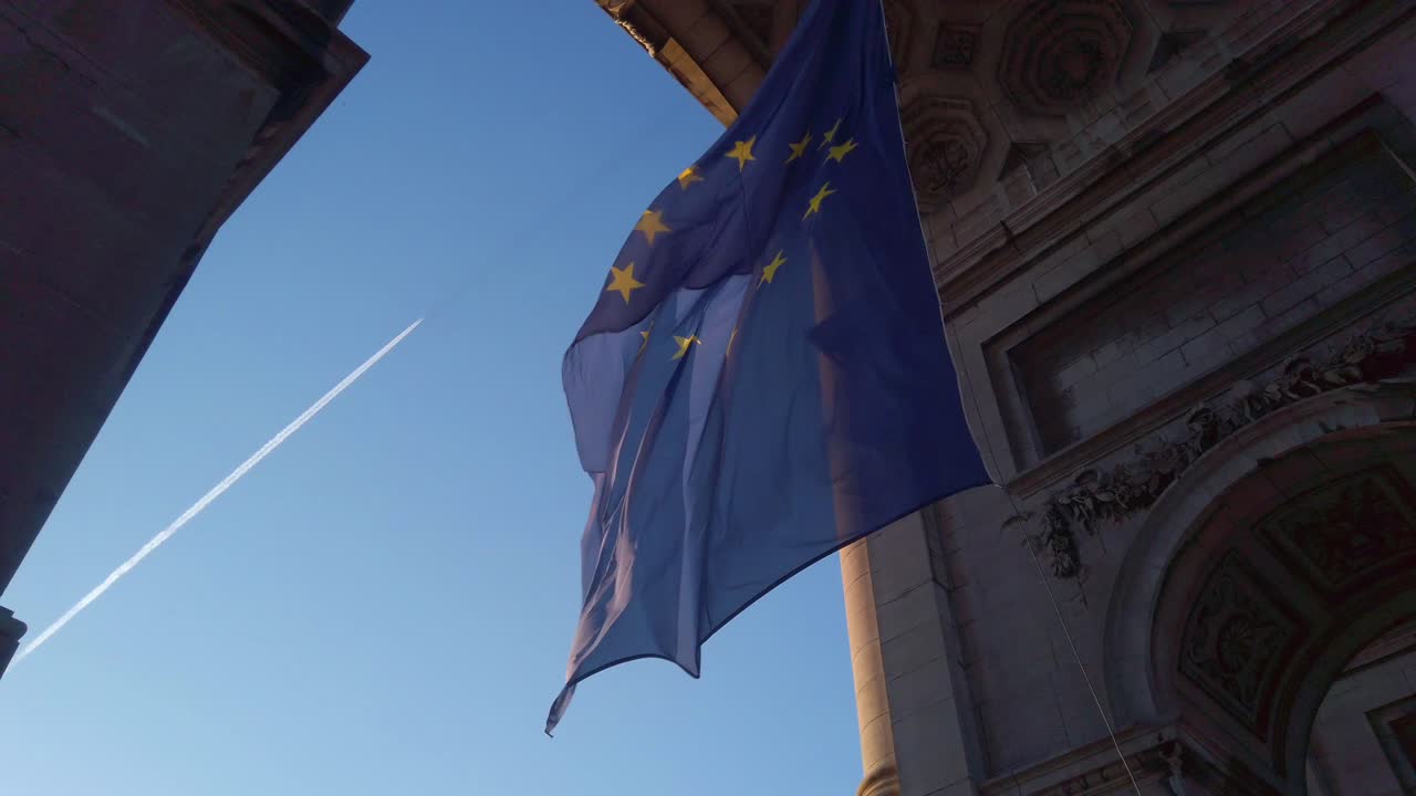 Euroopan unionin lippu liehuu hidastettuna kaaren alla lentokoneen vanan kanssa, mikä kuvastaa kestävän ilmailupolitiikan tavoitteita