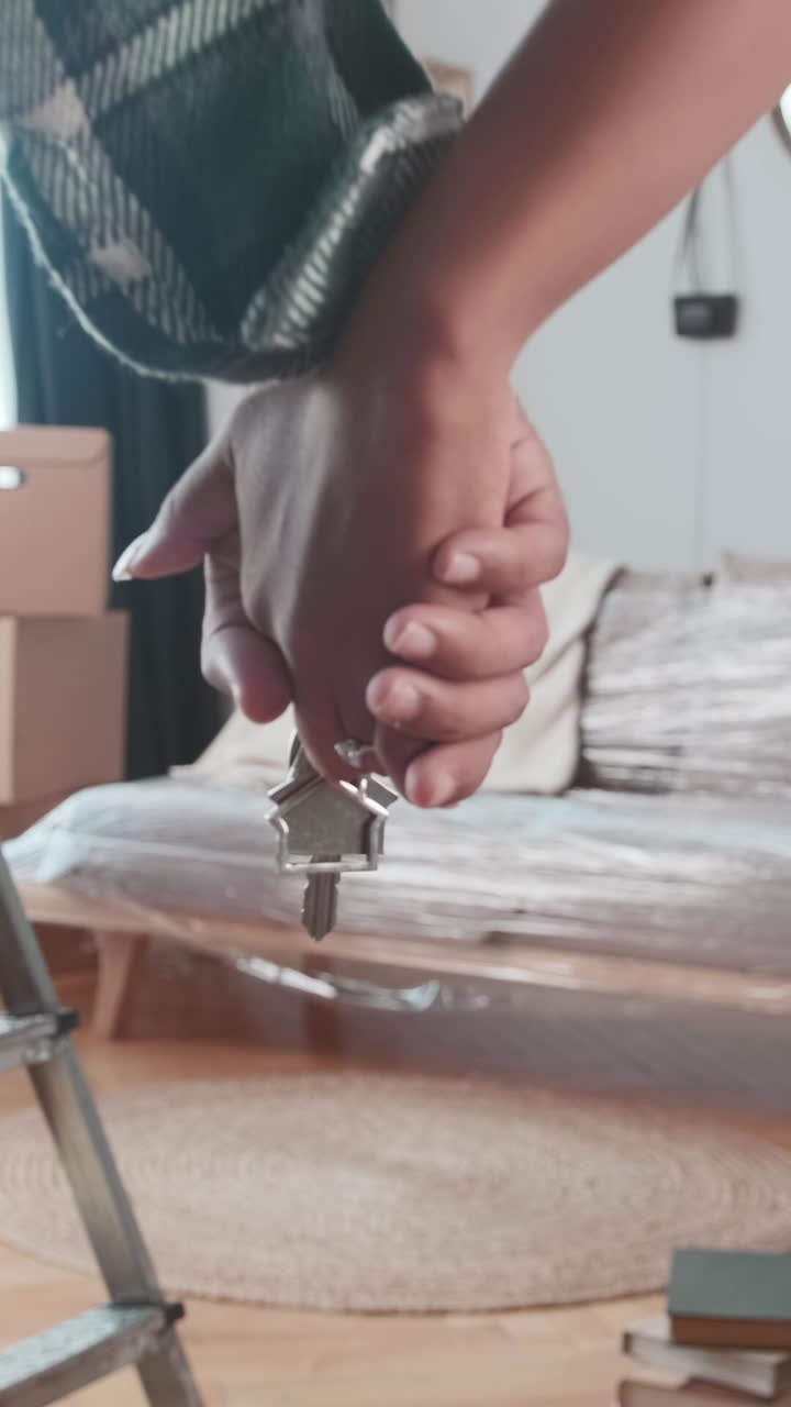 House keys of man and woman holding hands after moving to new home