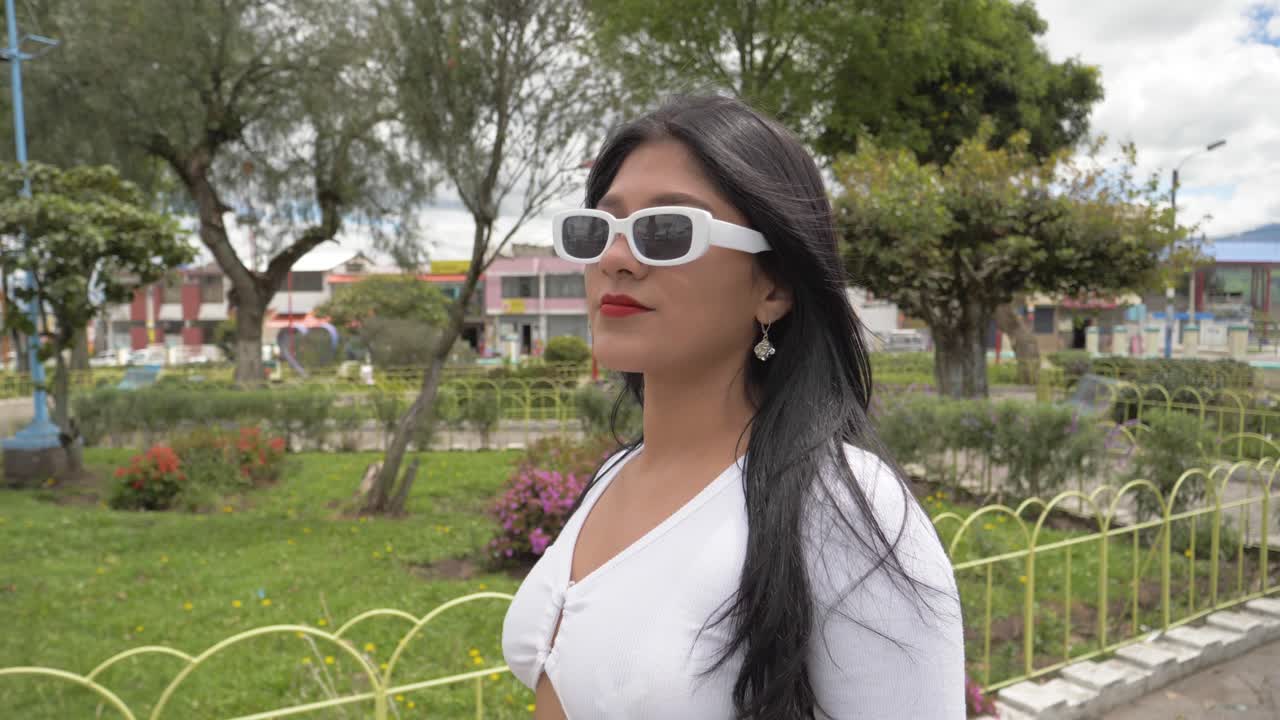 clip cinematográfico en primer plano de una joven latina con gafas de sol caminando con confianza en un día soleado