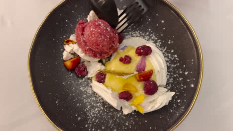 un postre dulce con helado y fruta fresca comido con cubiertos