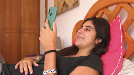 girl laughing doing video chat using mobile phone in bed