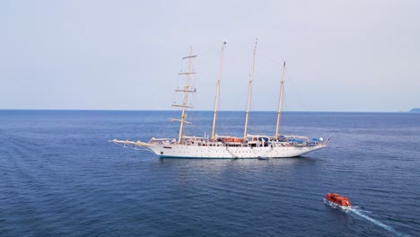 elegant four-masted sailing yacht anchored beside the iconic rock of monemvasia, surrounded by the calm aegean waters under the bright summer sun