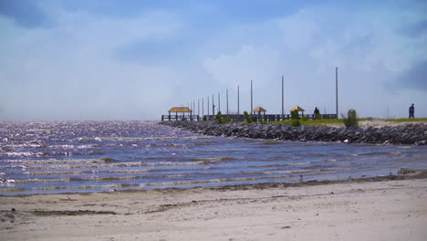 gente caminando con aparejos de pesca en un muelle de piedra en un hermoso día soleado en la costa de mississippi