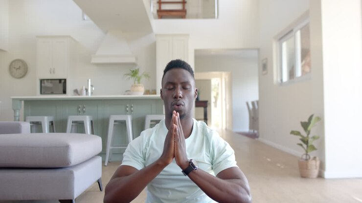 Focused african american man practising yoga meditation in sunny living room, slow motion