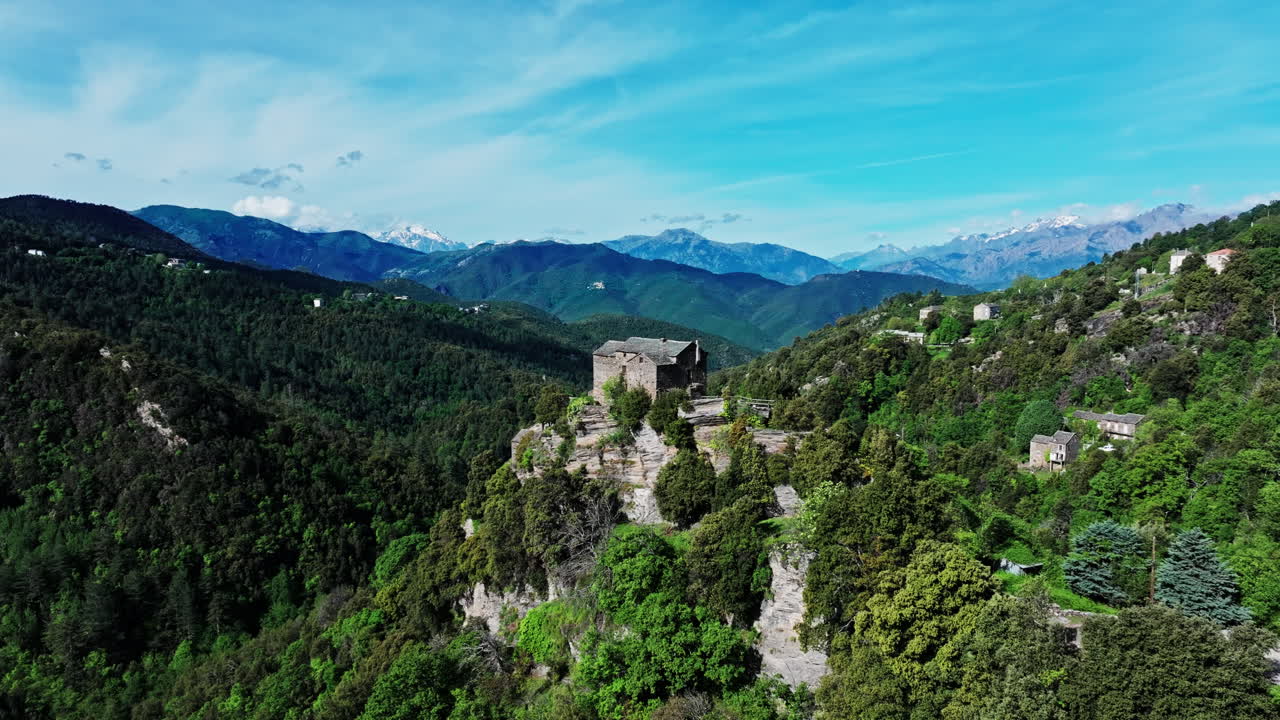 Aerial drone shot over the green lush landscape of inland Corsica, France. High view of the landscape and the mountains in the distance. Summer holidays destination for hikers and mountain lovers