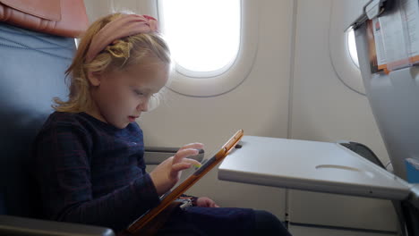 kid using tablet computer to draw in the airplane