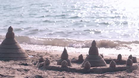 sandcastle against ocean rippling water reflecting sunlight