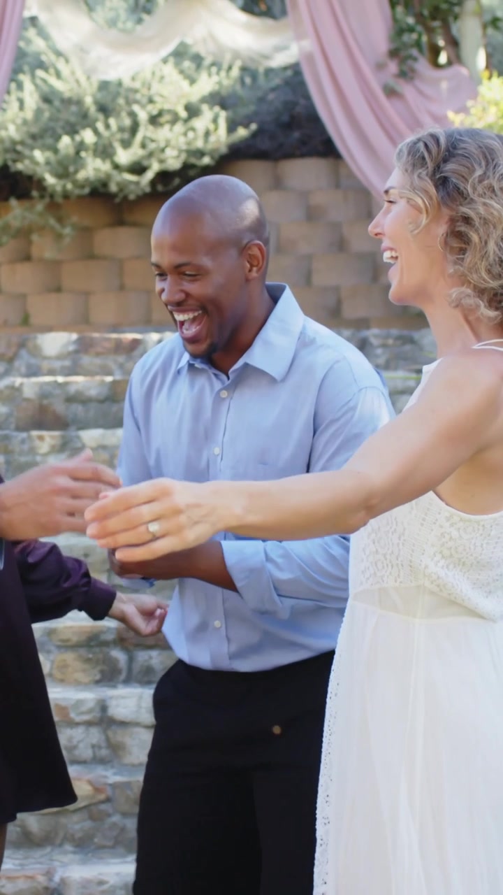 Video verticale: Sposa in abito bianco che si protende verso un uomo in blu, salutando, abbracciando e ballando a un matrimonio.