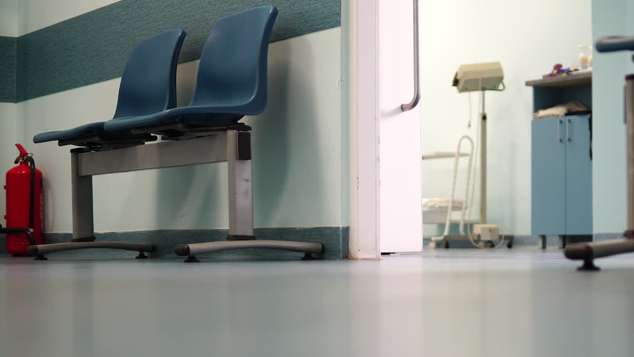 Sala de espera vazia no hospital, portas abertas do consultório médico, cadeiras desocupadas no corredor do hospital, da esquerda para a direita