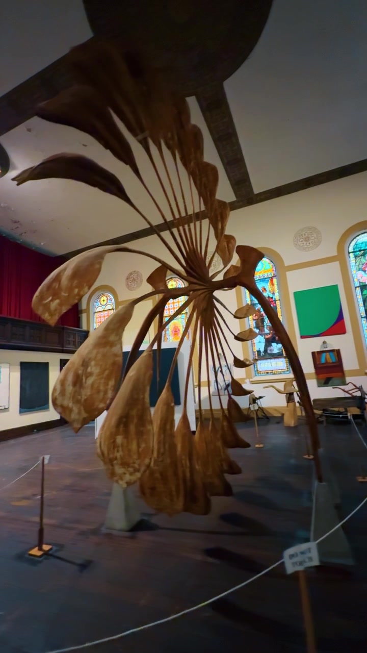 Jim Thorpe, USA, 27 luglio 2025: Scultura in legno organica in galleria storica. Vista dettagliata di una grande scultura in legno dalla forma organica esposta all'interno di una galleria di chiesa storica con vetrate colorate.