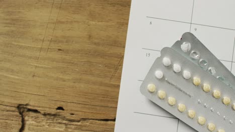 video of close up of yellow tablets over calendar on wooden table