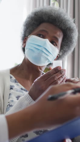 african american female doctor and senior female patient in face masks