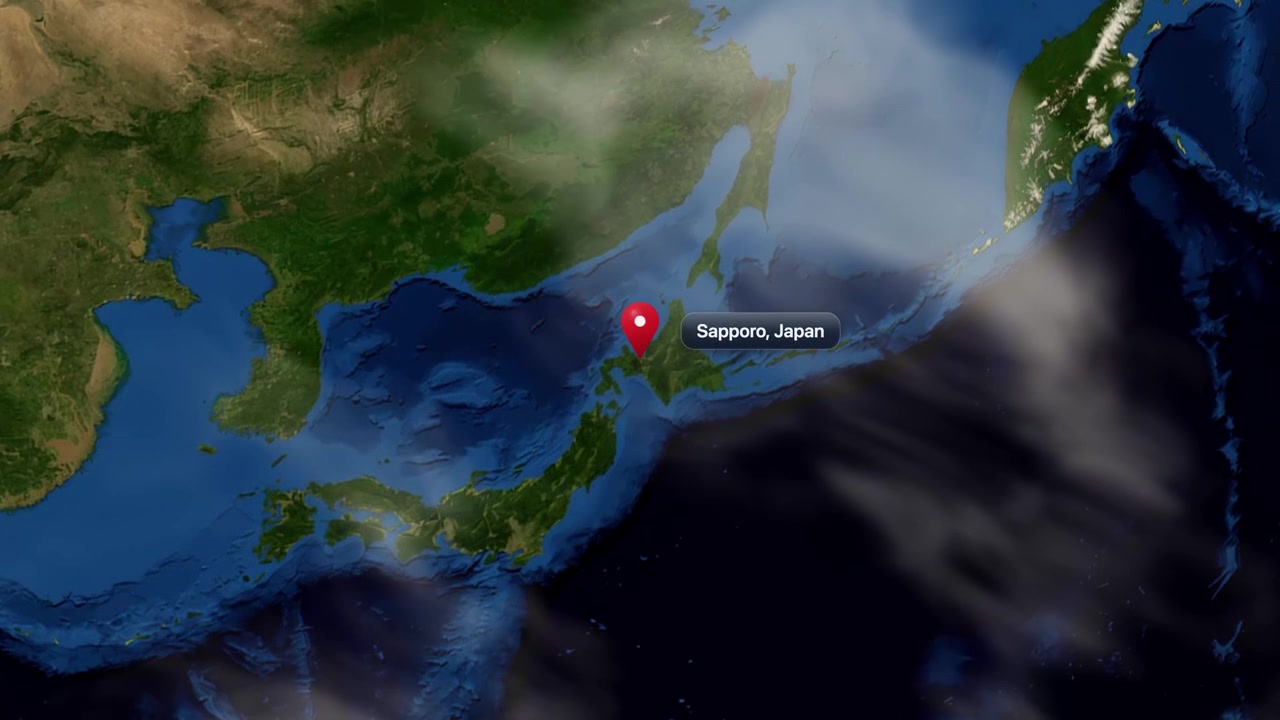 Satellite camera zooms from outer space into East Asia, marking Sapporo, Japan with pin. Includes NASA public domain imagery.