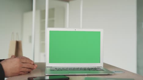 primer plano de la pantalla de un portátil con llave de croma, dos manos masculinas temblando en el fondo