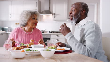 Happy-senior-black-couple-talking-and-enjoying-their-Sunday-dinner-together-at-home,-close-up