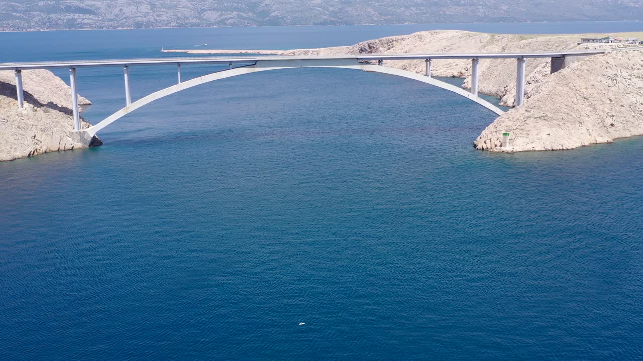 Arch bridge of Paski Most linking Otok Pag island to the Croatian mainland with an abandoned fort in the foreground, Aerial dolly out shot