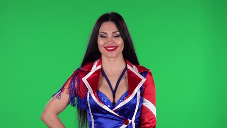 portret van een mooie vrouw in een verleidelijk pak in rode blauwe witte kleuren met rhinestones kijkt recht en glimlacht. groen scherm