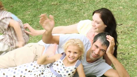 happy family on the grass waving at the camera